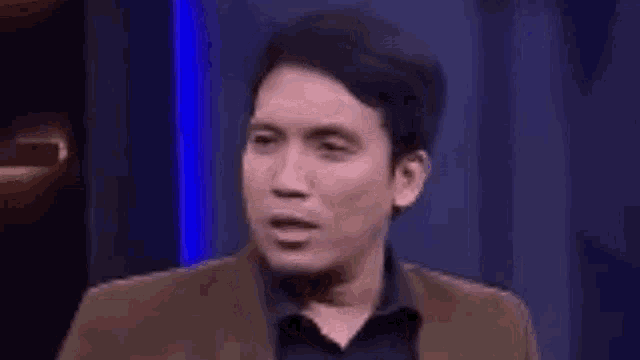 a man in a suit is making a surprised face .