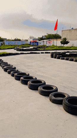 a man is riding a go kart on a track with tires lined up in front of him