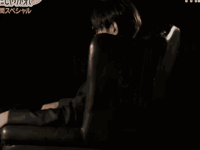 a man in a suit and sunglasses is sitting in a chair with chinese writing on the bottom
