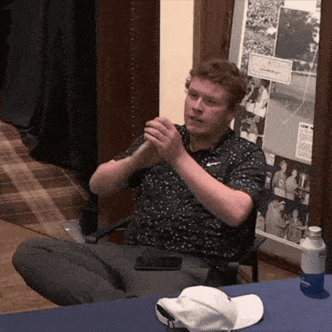 a man sits at a table with a bottle of aquafina on it