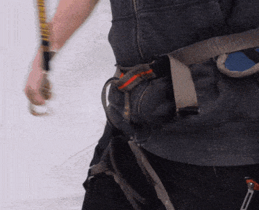 a person wearing a gray vest with a belt around their waist with a red and orange stripe