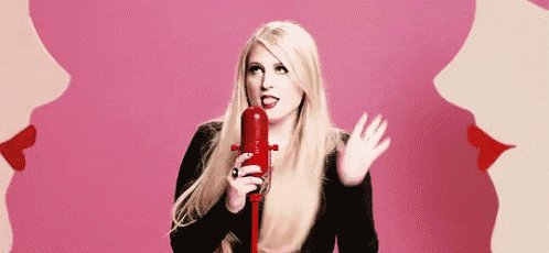 a woman is singing into a red microphone in front of two women 's lips .