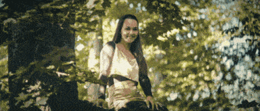 a woman is sitting on a tree branch smiling