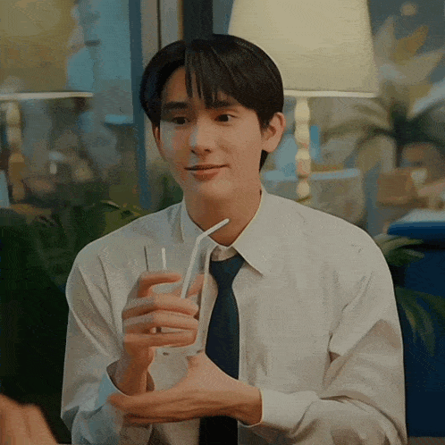 a man in a white shirt and tie is holding a glass with a straw in it