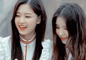 two girls are standing next to each other smiling and laughing .