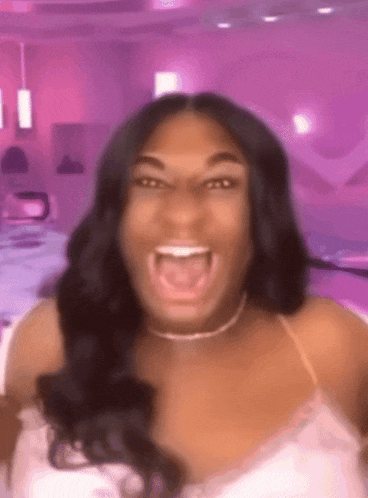 a woman is making a funny face with her mouth open in front of a pink background .