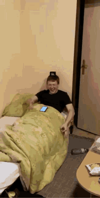 a man is sitting on a bed with a cell phone on his head .