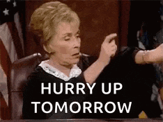 a woman is sitting at a table with a sign that says hurry up tomorrow on it .