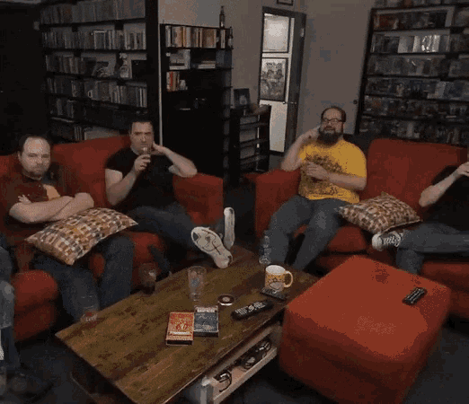 a group of men are sitting on a couch with a coffee table and a book on it that says ' a man '
