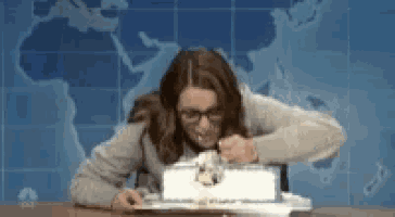 a woman is sitting at a desk with a cake on it .