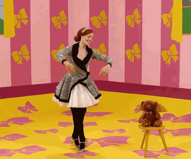 a woman is dancing in front of a teddy bear