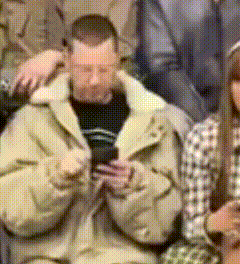 a man wearing a tan jacket is looking at his phone