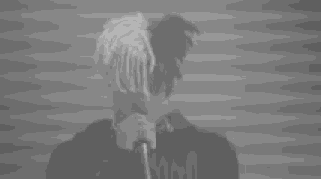 a man with dreadlocks is holding a microphone in front of his face in a black and white photo .