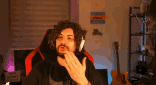 a man with curly hair is wearing headphones and making a funny face .