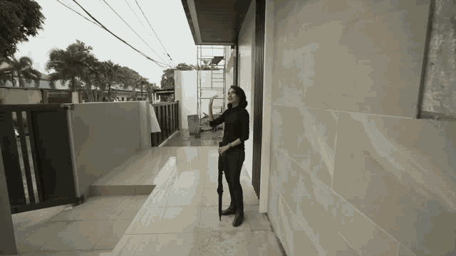 a woman holding an umbrella is standing in front of a building