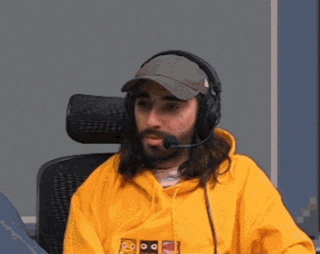 a man with long hair and a beard wearing headphones and a yellow hoodie .