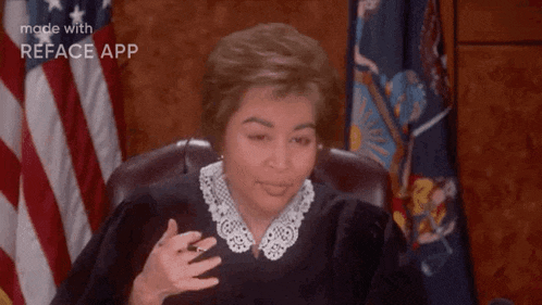 a judge is sitting in a courtroom with an american flag in the background and making a funny face .