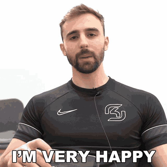 a man with a beard is wearing a black nike shirt and says i 'm very happy