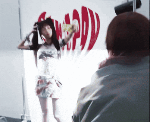 a woman is taking a picture of herself in front of a wall that has the word coca cola on it