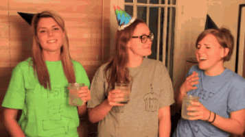 a woman wearing a party hat is standing with two other women holding drinks