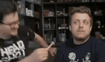a man is talking into a microphone while another man holds a stick in front of him .