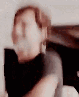 a blurry picture of a person 's face with a black shirt on and a black scarf around their neck .
