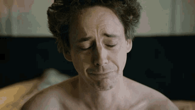 a shirtless man with his eyes closed looks sad