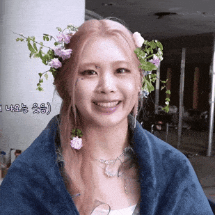 a woman with flowers in her hair is smiling and wrapped in a blue towel