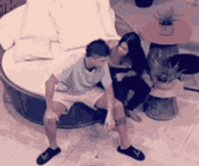 a man and a woman are sitting next to each other on a round couch .