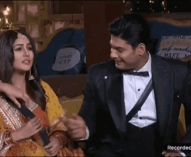 a man in a tuxedo is talking to a woman in a traditional dress .