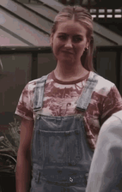 a woman wearing overalls and a t-shirt with the letter d on the bottom right