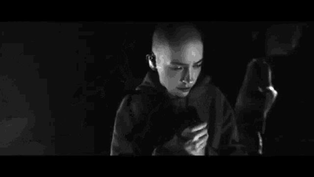 a bald woman is holding a microphone in a black and white photo .