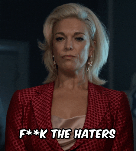 a woman in a red jacket is saying f * * k the haters