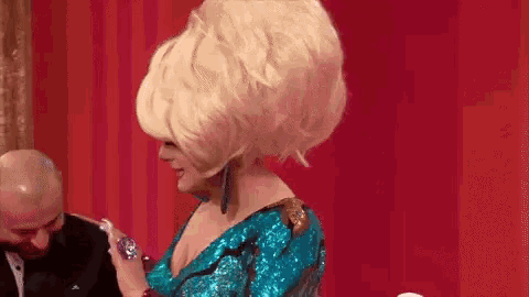 a woman in a wig is standing next to a man in a tuxedo .