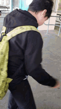 a person wearing a black jacket and a yellow backpack with the word fila on the strap