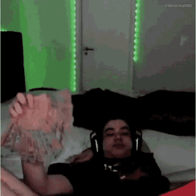 a man is laying on a bed wearing headphones and a black shirt .