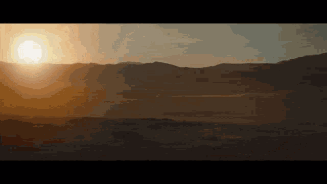 the sun is setting behind the mountains in the desert
