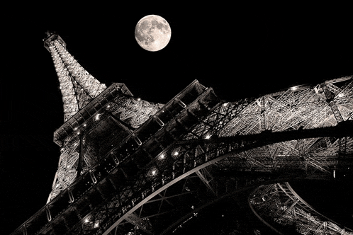 the eiffel tower is lit up at night with the full moon in the background
