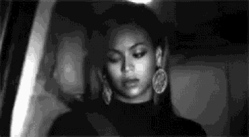 a black and white photo of a woman wearing earrings and a turtleneck .
