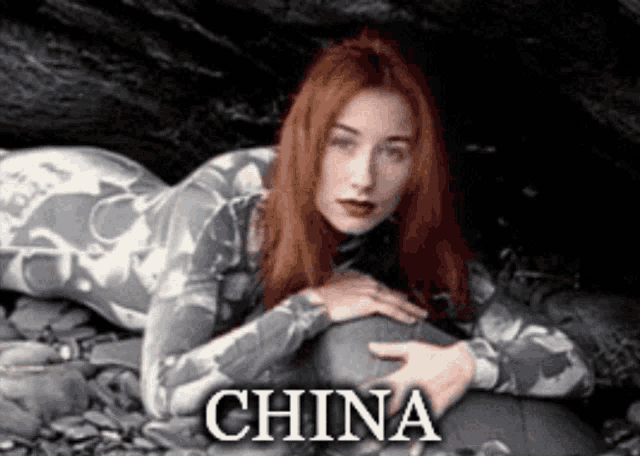 a woman with red hair is laying on a rock and the word china is on the bottom