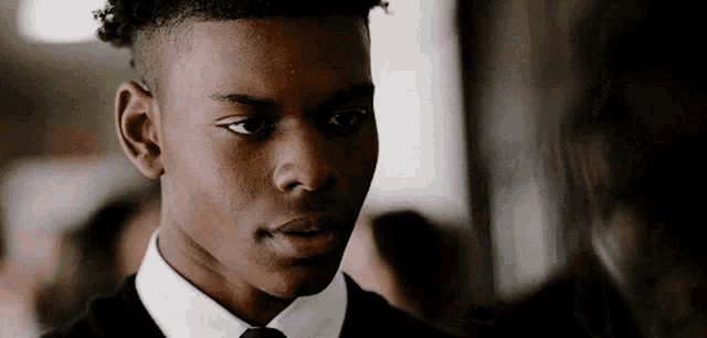 a young man in a suit and tie looks at the camera with a serious look on his face