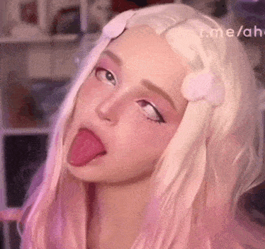 a girl with long blonde hair is sticking her tongue out .