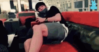 a man is sitting on a couch with his legs crossed and a mask on his face .