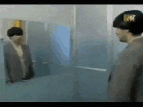 a man in a suit is standing in front of a mirror looking at himself