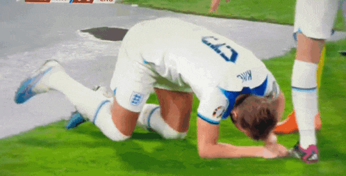 a soccer player with the number 5 on his jersey kneeling on the field