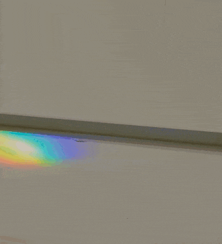 a rainbow is reflected in a white wall