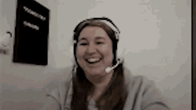 a woman wearing headphones and a microphone is smiling while having a video call .