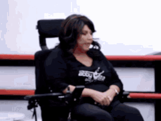 a woman is sitting in a wheelchair wearing a black shirt that says ' body ' on it
