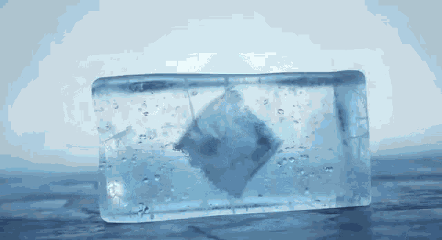 a block of ice is sitting on a wooden table with bubbles coming out of it .