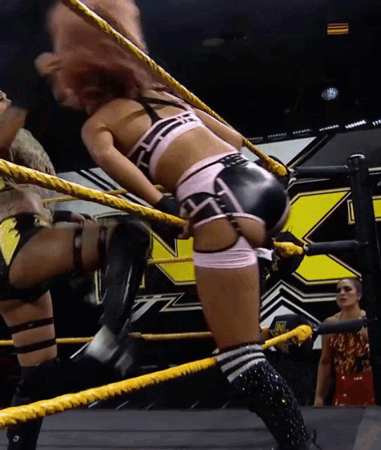two women wrestling in a ring with the letter x on the wall